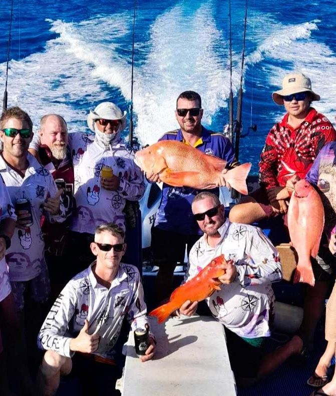 A Group of People Standing Next to a Boat That Says Fishing Charters — Whitsunday Fishing Charters In Airlie Beach, QLD