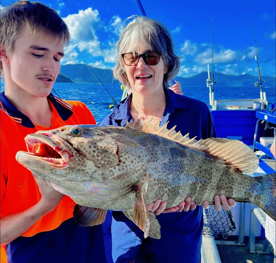 A Man and a Woman Are Holding a Large Fish in Their Hands — Whitsunday Fishing Charters In Airlie Beach, QLD