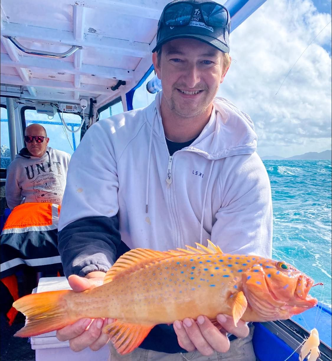 Man on a Boat is Holding a Fish in His Hands — Whitsunday Fishing Charters In Airlie Beach, QLD