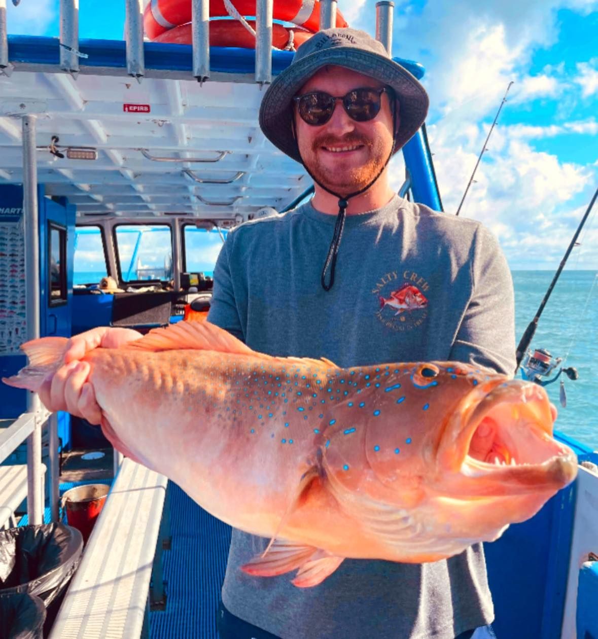 Man is Holding a Large Fish on a Boat — Whitsunday Fishing Charters In Airlie Beach, QLD