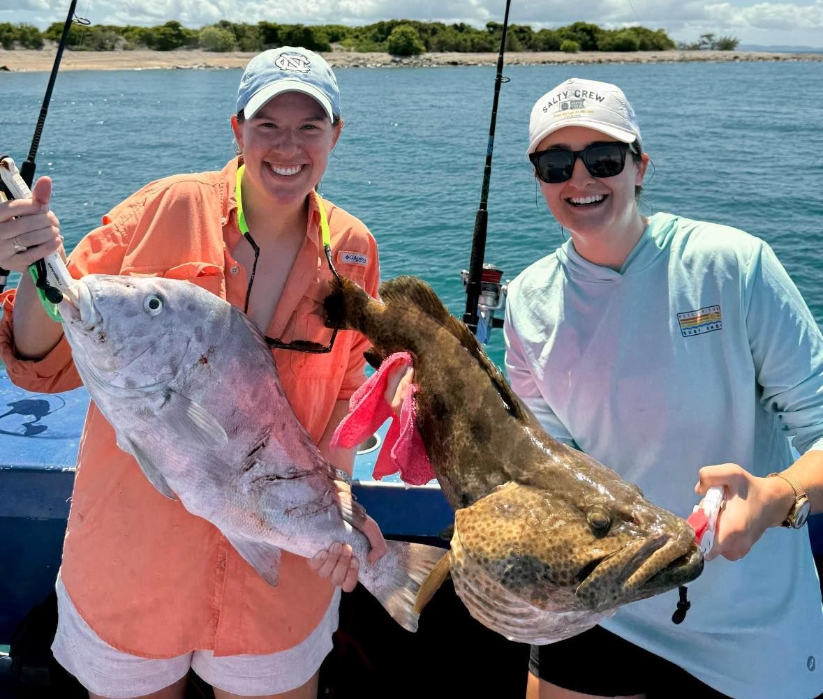 Two Women Are Holding a Large Fish on a Boat — Whitsunday Fishing Charters In Airlie Beach, QLD
