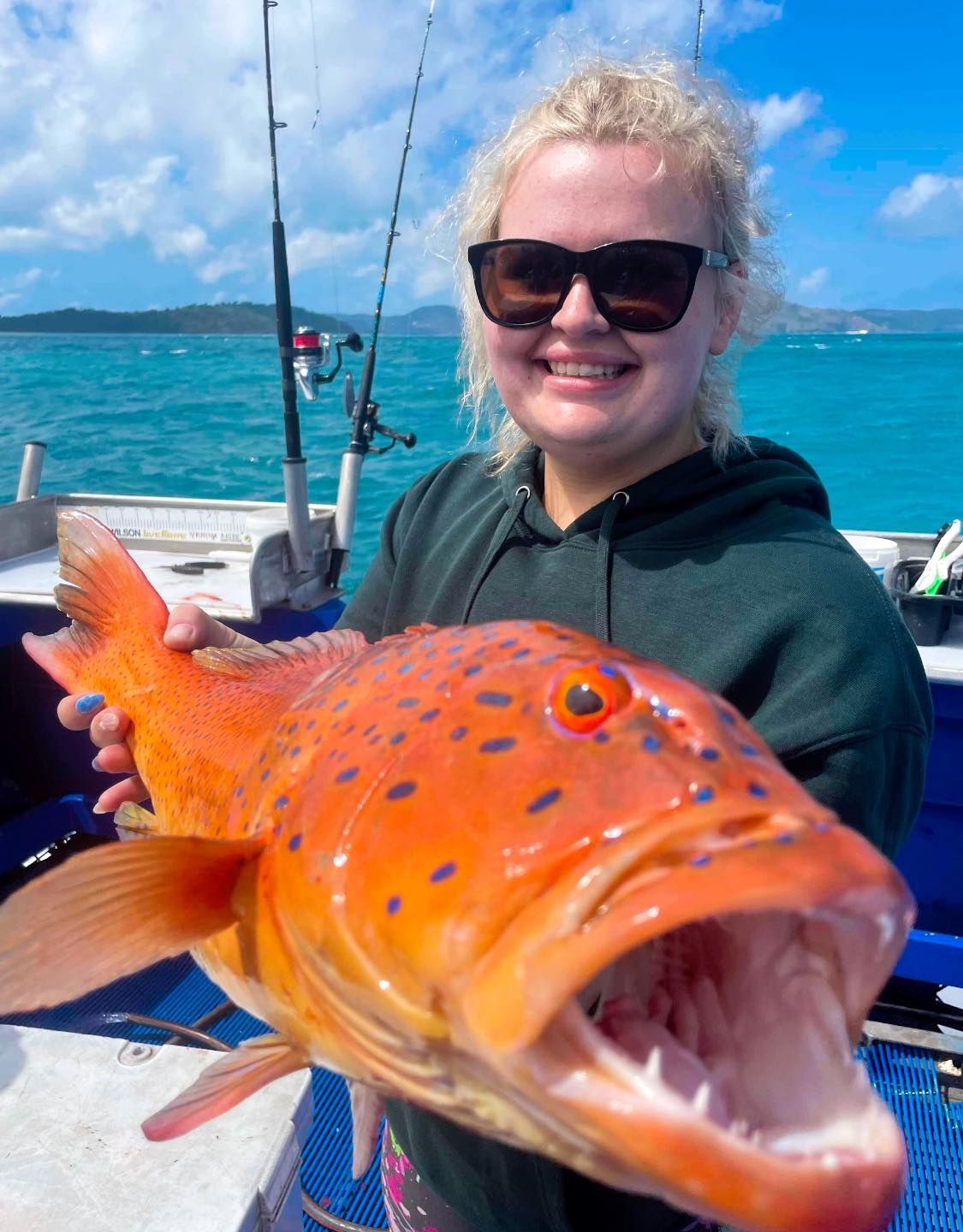 A Woman is Holding a Large Red Fish in Her Hands — Whitsunday Fishing Charters In Airlie Beach, QLD