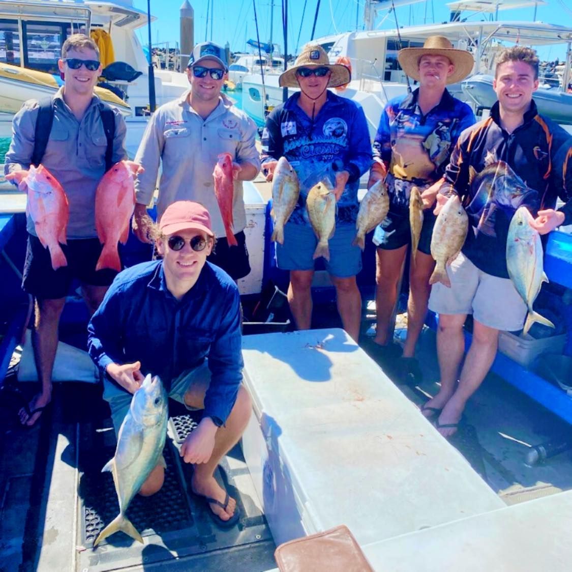 A Group of People Holding Fish on a Boat — Whitsunday Fishing Charters In Airlie Beach, QLD