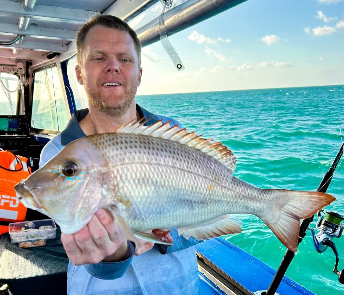 A Man is Holding a Large Fish in His Hands on a Boat — Whitsunday Fishing Charters In Airlie Beach, QLD