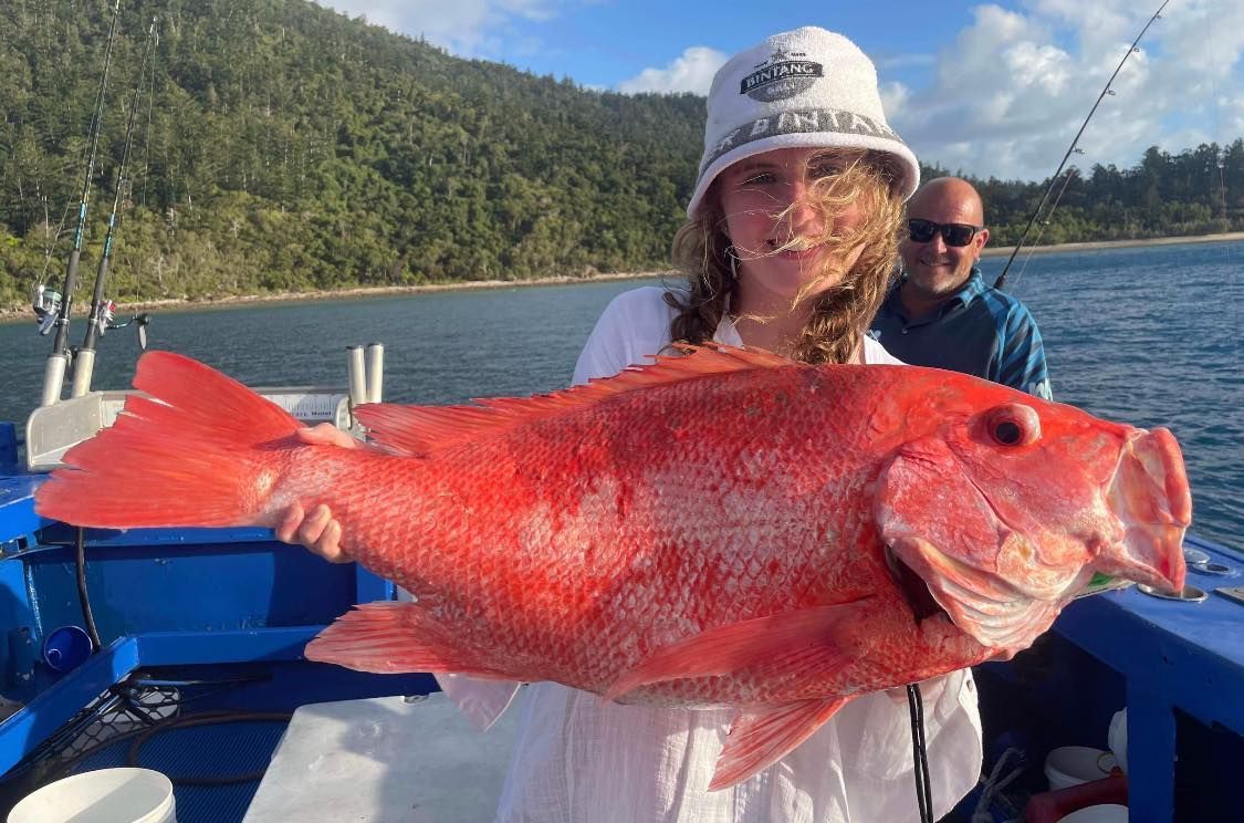 A Woman is Holding a Large Red Fish on a Boat — Whitsunday Fishing Charters In Airlie Beach, QLD