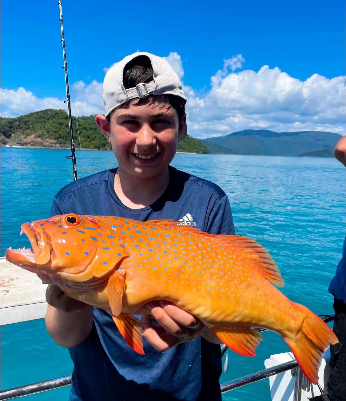 A Young Boy is Holding a Large Fish in His Hands on a Boat — Whitsunday Fishing Charters In Airlie Beach, QLD