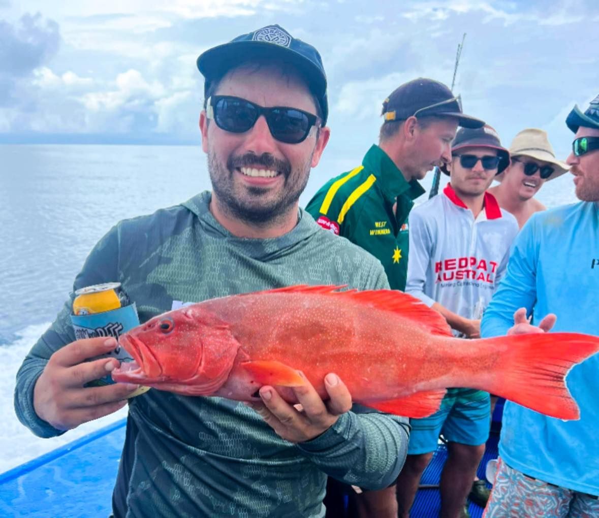 A Man is Holding a Large Red Fish in His Hands — Whitsunday Fishing Charters In Airlie Beach, QLD