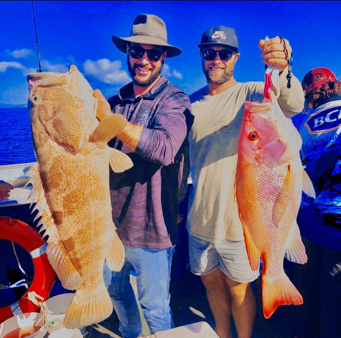 Two Men Are Holding Fish In Front Of A Boat That Says Hc On It — Whitsunday Fishing Charters In Airlie Beach, QLD