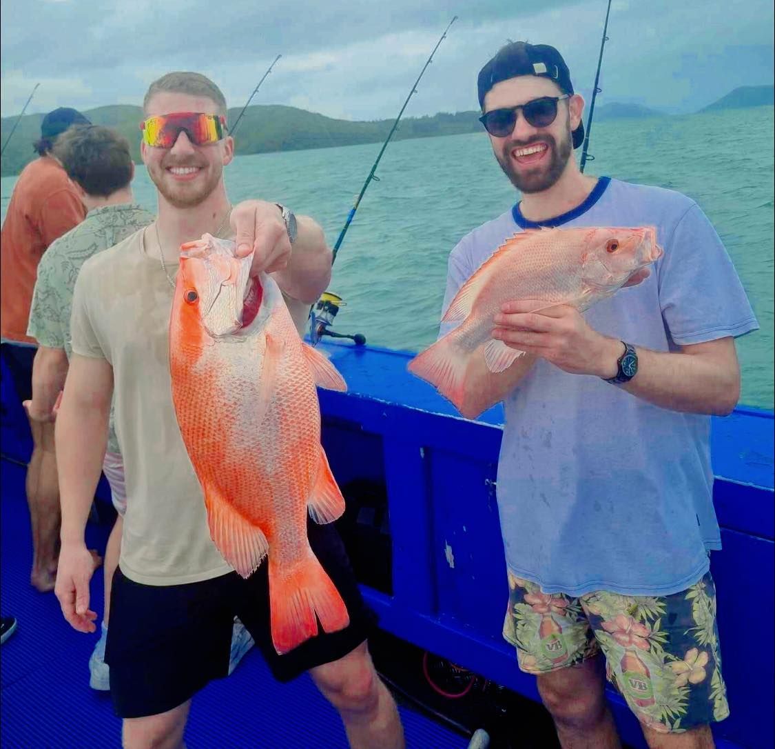 Two Men Are Standing on a Boat Holding Fish — Whitsunday Fishing Charters In Airlie Beach, QLD