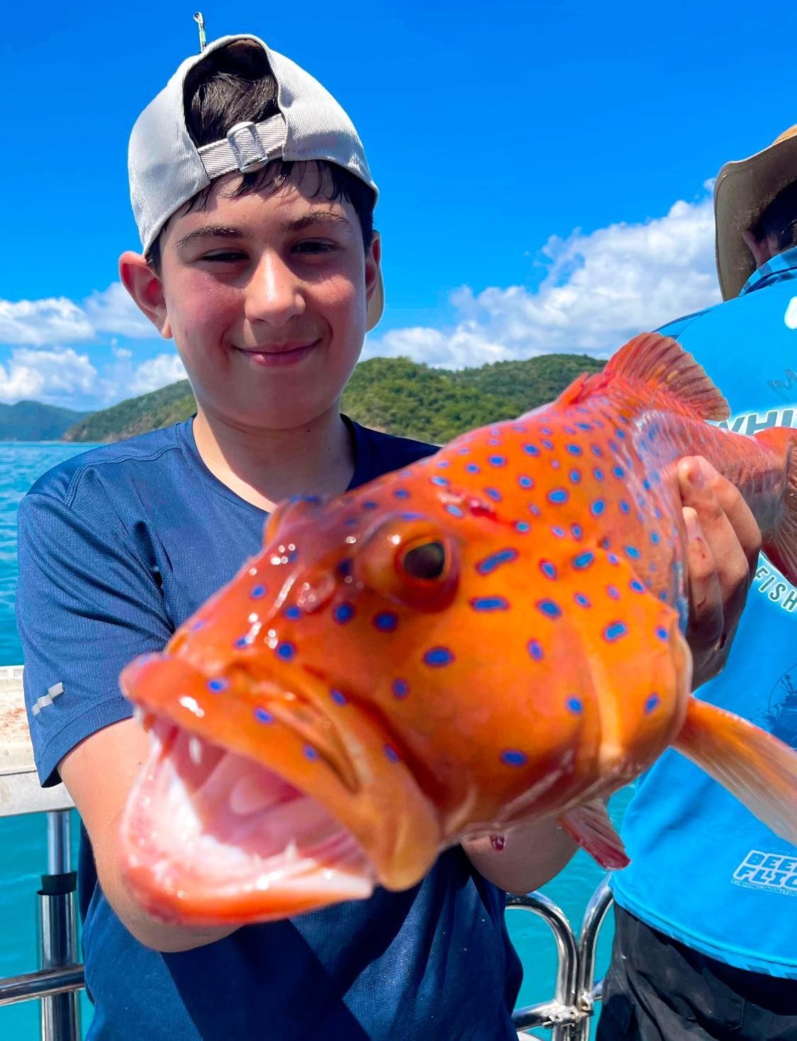 A Young Boy is Holding a Large Fish in His Hands — Whitsunday Fishing Charters In Airlie Beach, QLD