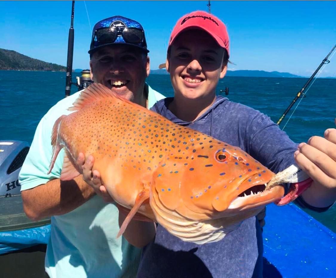 A Man and a Woman Are Holding a Large Fish on a Boat — Whitsunday Fishing Charters In Airlie Beach, QLD