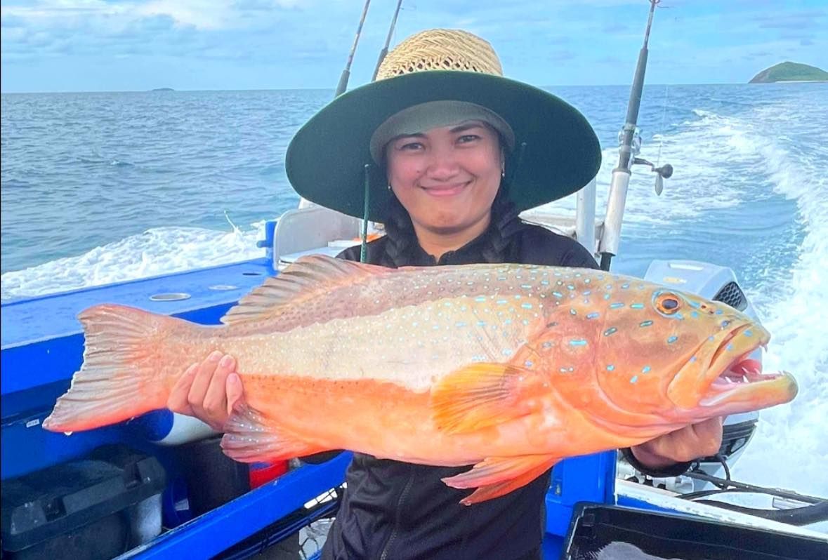 A Woman is Holding a Large Red Fish on a Boat — Whitsunday Fishing Charters In Airlie Beach, QLD