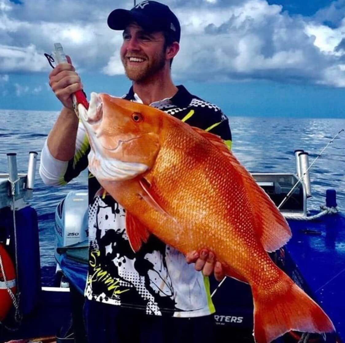 A Man is Holding a Large Orange Fish in His Hands — Whitsunday Fishing Charters In Airlie Beach, QLD