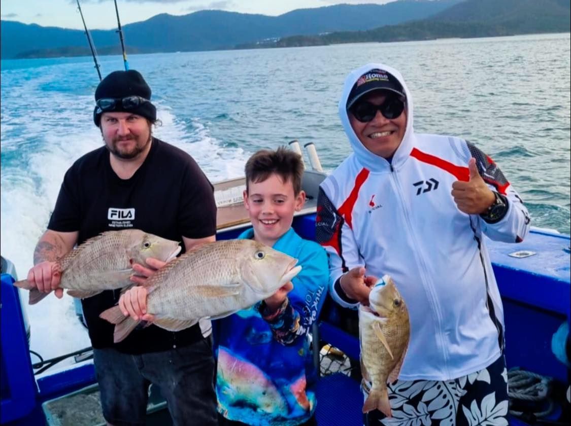 Two Men and a Boy Are Holding Fish on a Boat — Whitsunday Fishing Charters In Airlie Beach, QLD