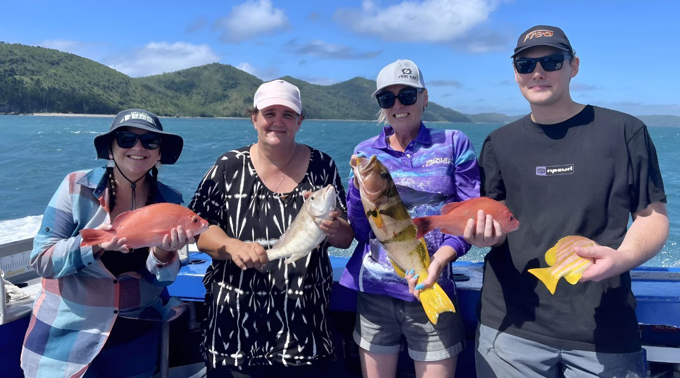 A Group of People Are Standing on a Boat Holding Fish — Whitsunday Fishing Charters In Airlie Beach, QLD
