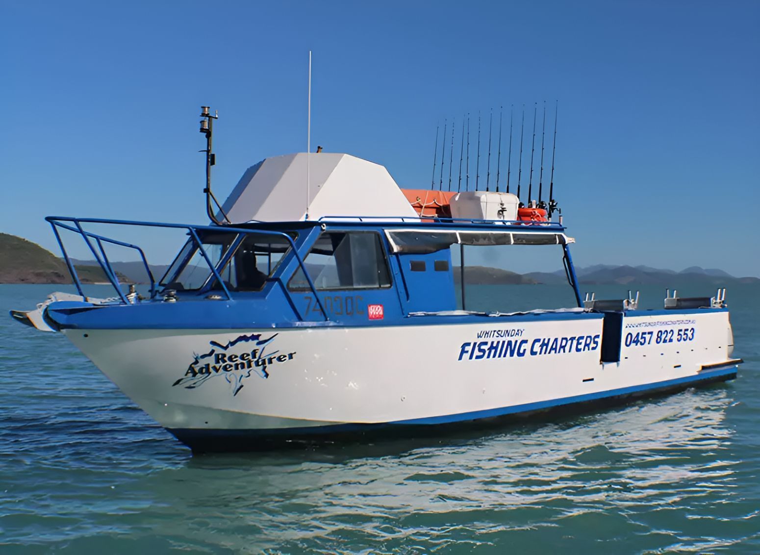 A Blue and White Fishing Charter Boat is Floating on the Water — Whitsunday Fishing Charters In Airlie Beach, QLD