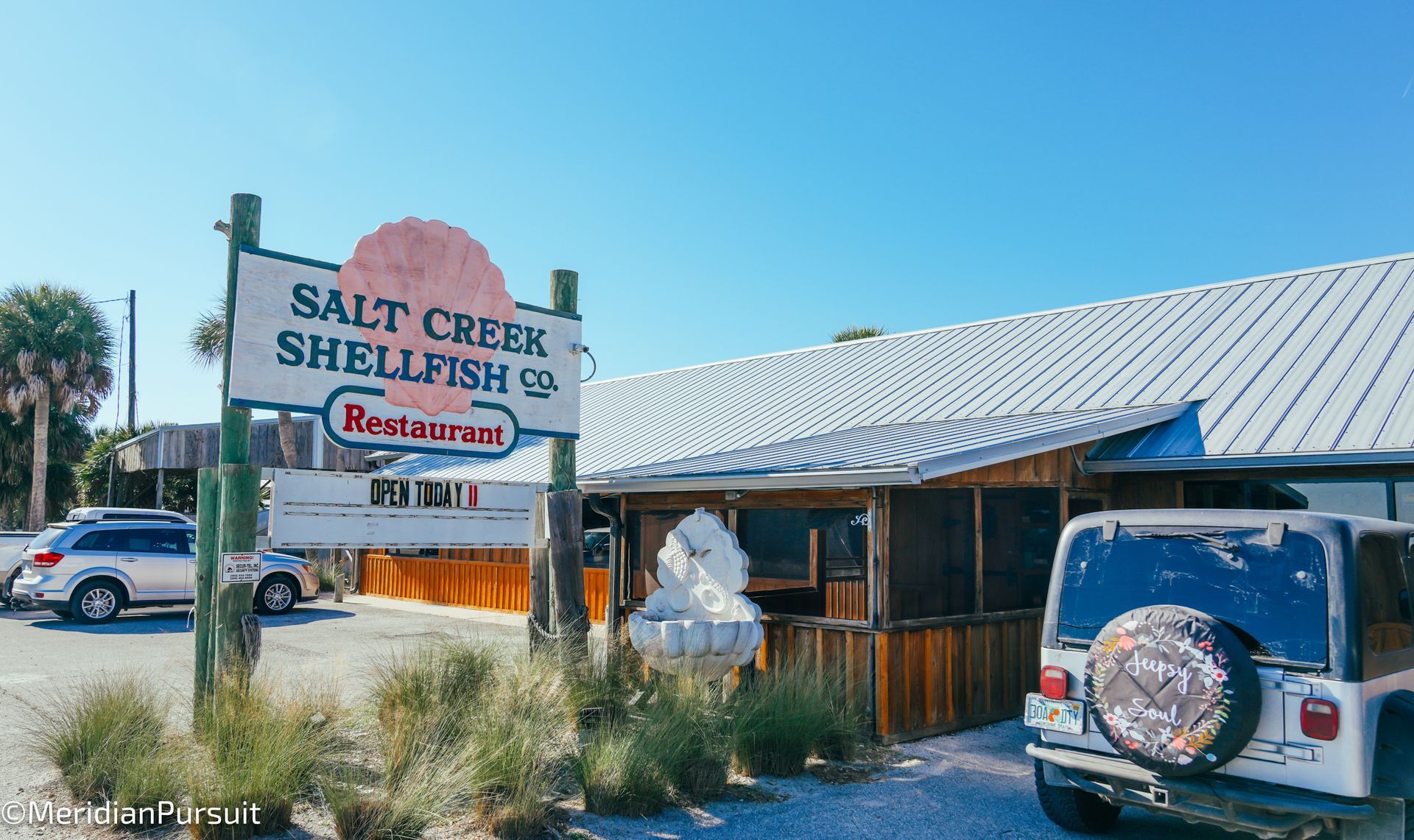 A car is parked in front of a restaurant called salt creek shellfish.