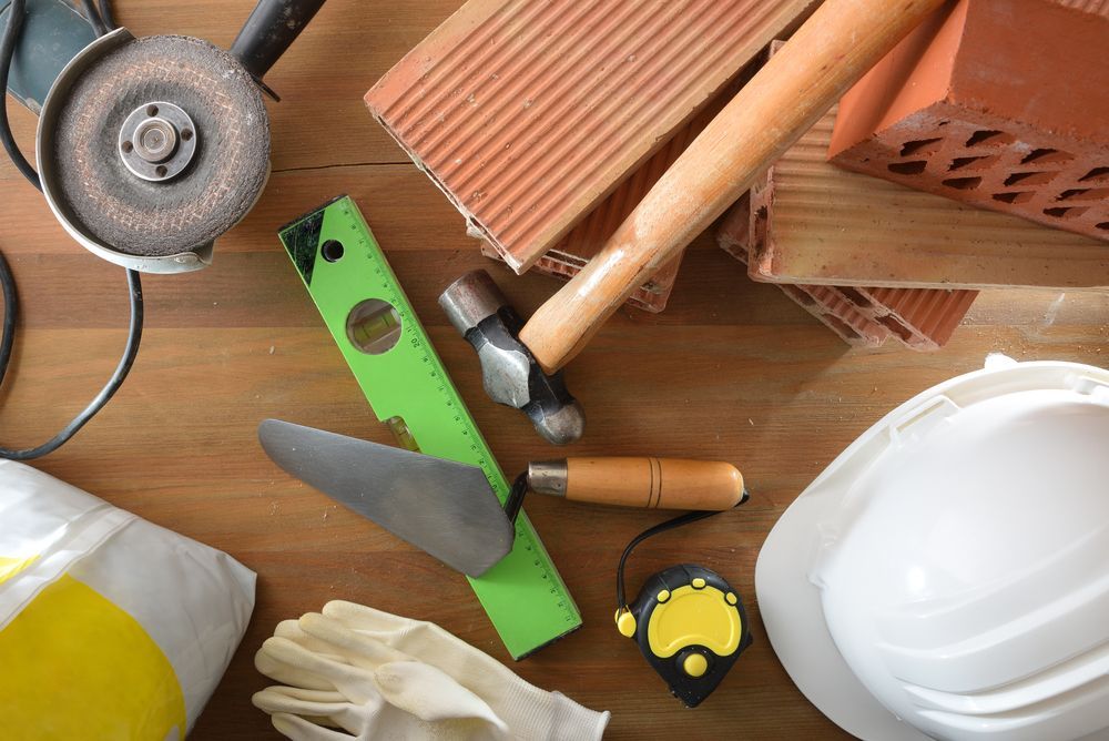 Un casco, guantes, herramientas y ladrillos están sobre una mesa de madera.