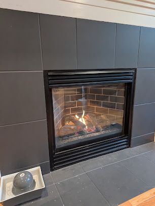 A fireplace with a glass door and a brick wall in a living room.