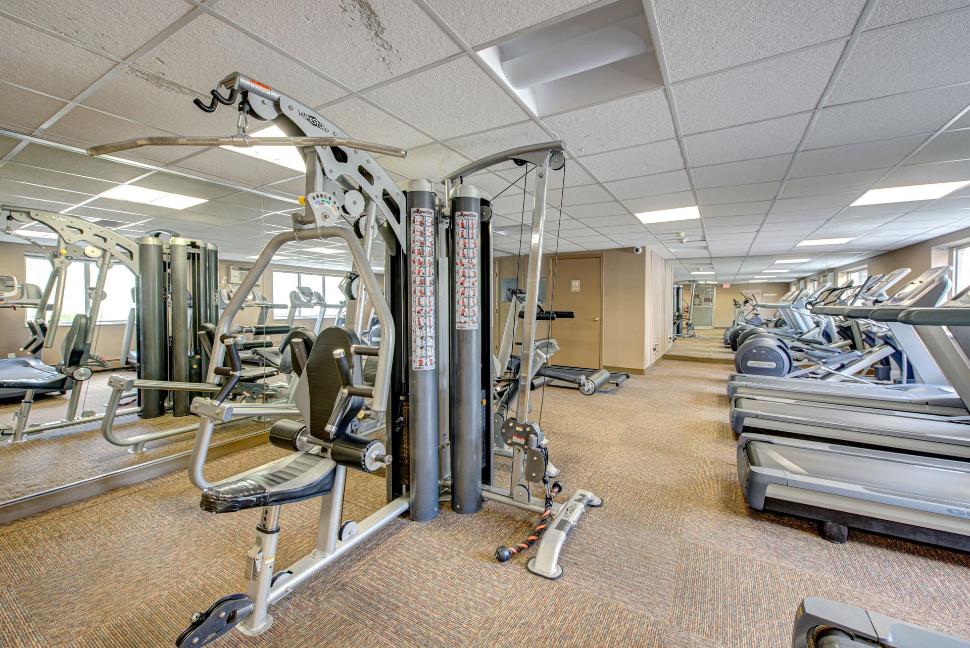 A large gym filled with lots of exercise equipment and mirrors.