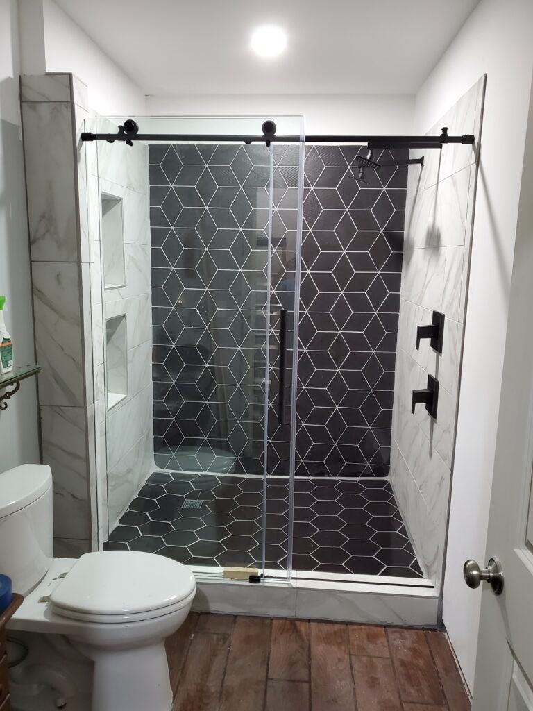 A bathroom with a toilet , shower and sliding glass door.