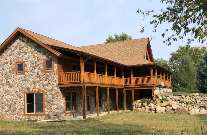 A large stone house with a wooden deck and porch