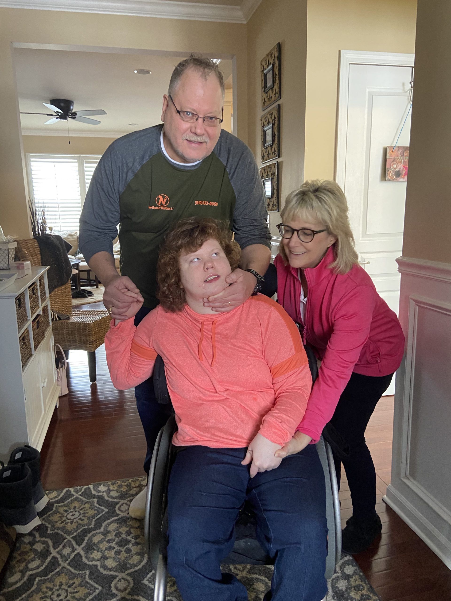 A man and two women are pushing a woman in a wheelchair.