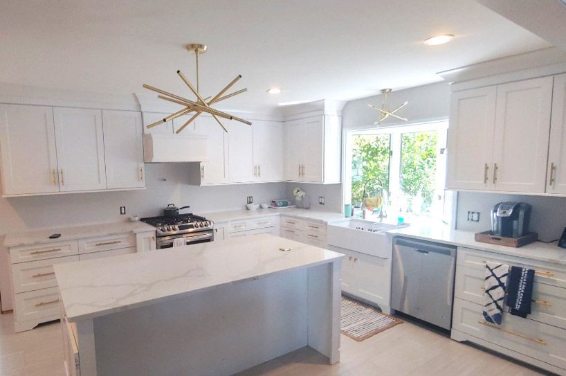 A kitchen with white cabinets , stainless steel appliances , and a large island.