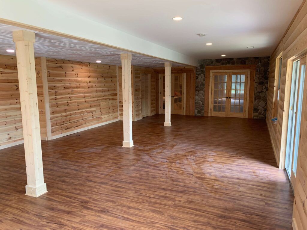 An empty room with wooden walls and hardwood floors in a log cabin.