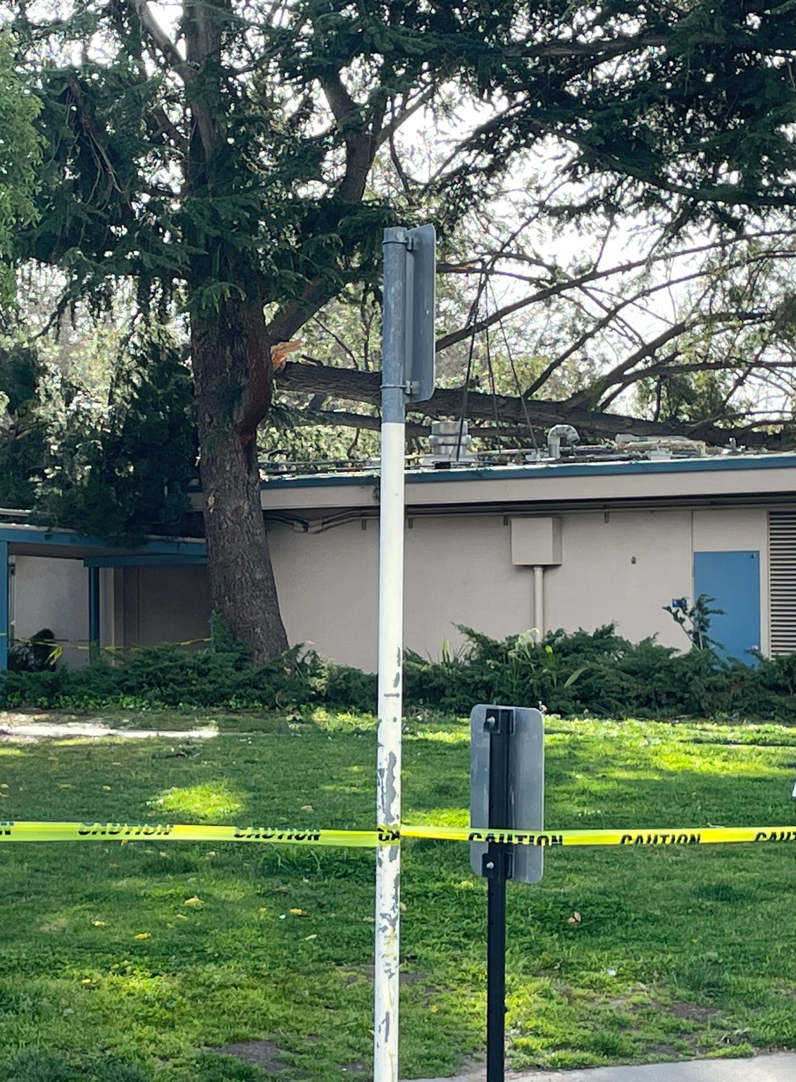 A white pole with a sign on it and a yellow caution tape around it