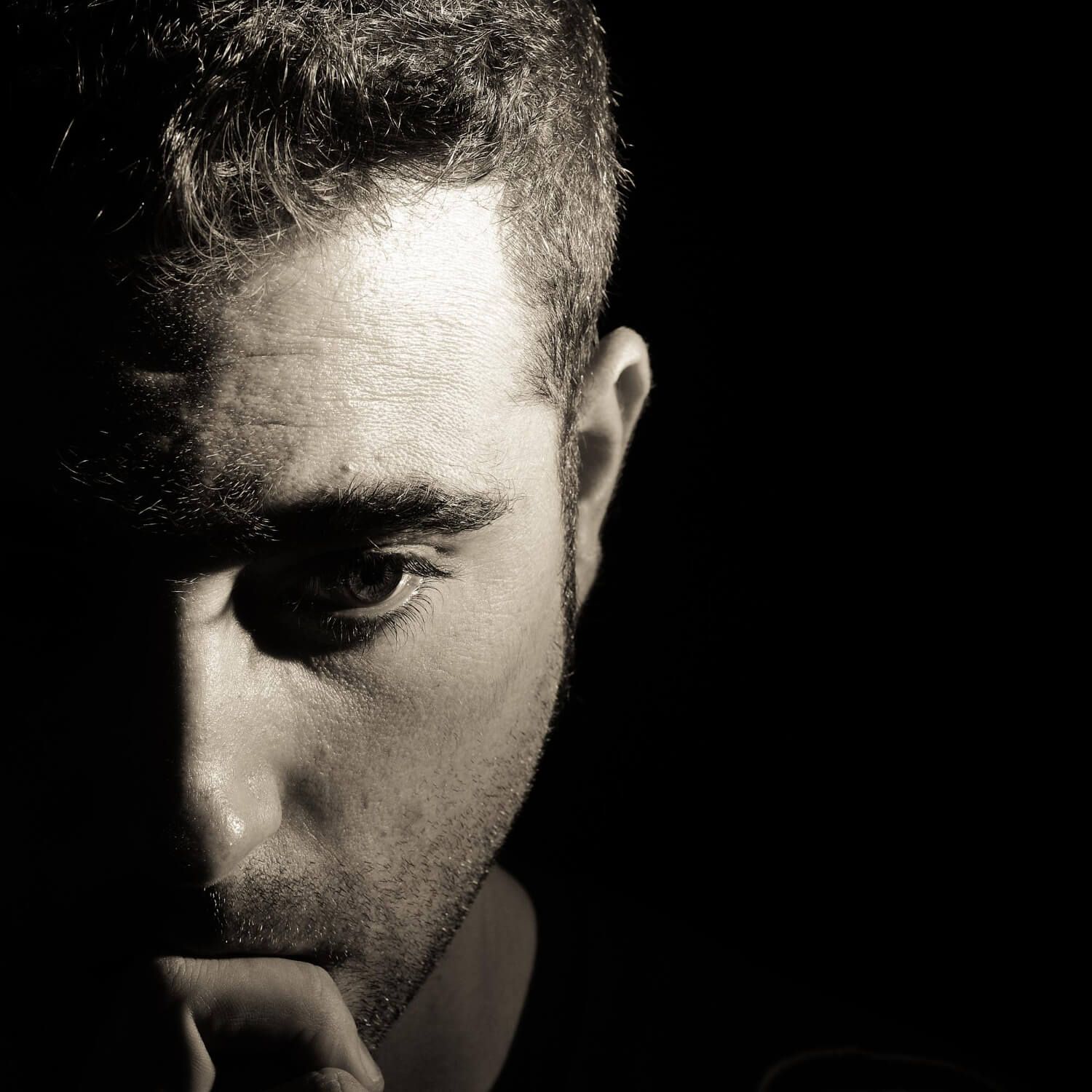 Black and white portrait of man in shadow representing the hidden nature of complex PTSD and trauma that runs deeper than traditional PTSD