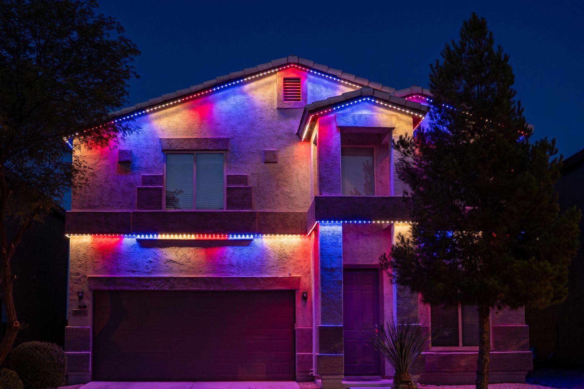 A house is decorated with red , white and blue christmas lights.
