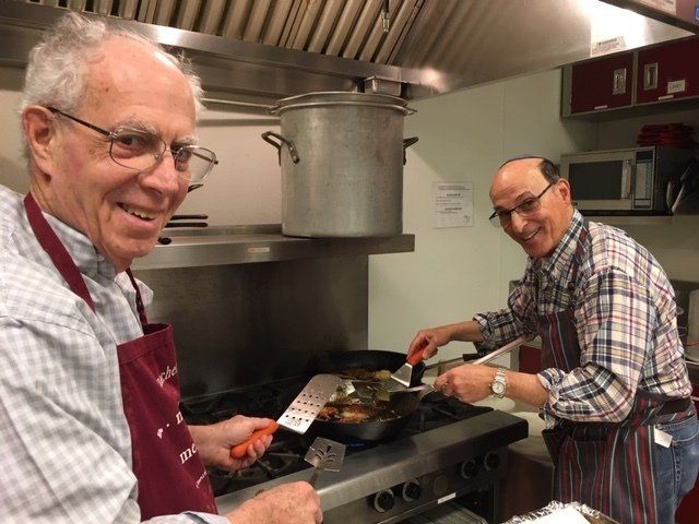 A photo of two smiling older white men in the kitchen