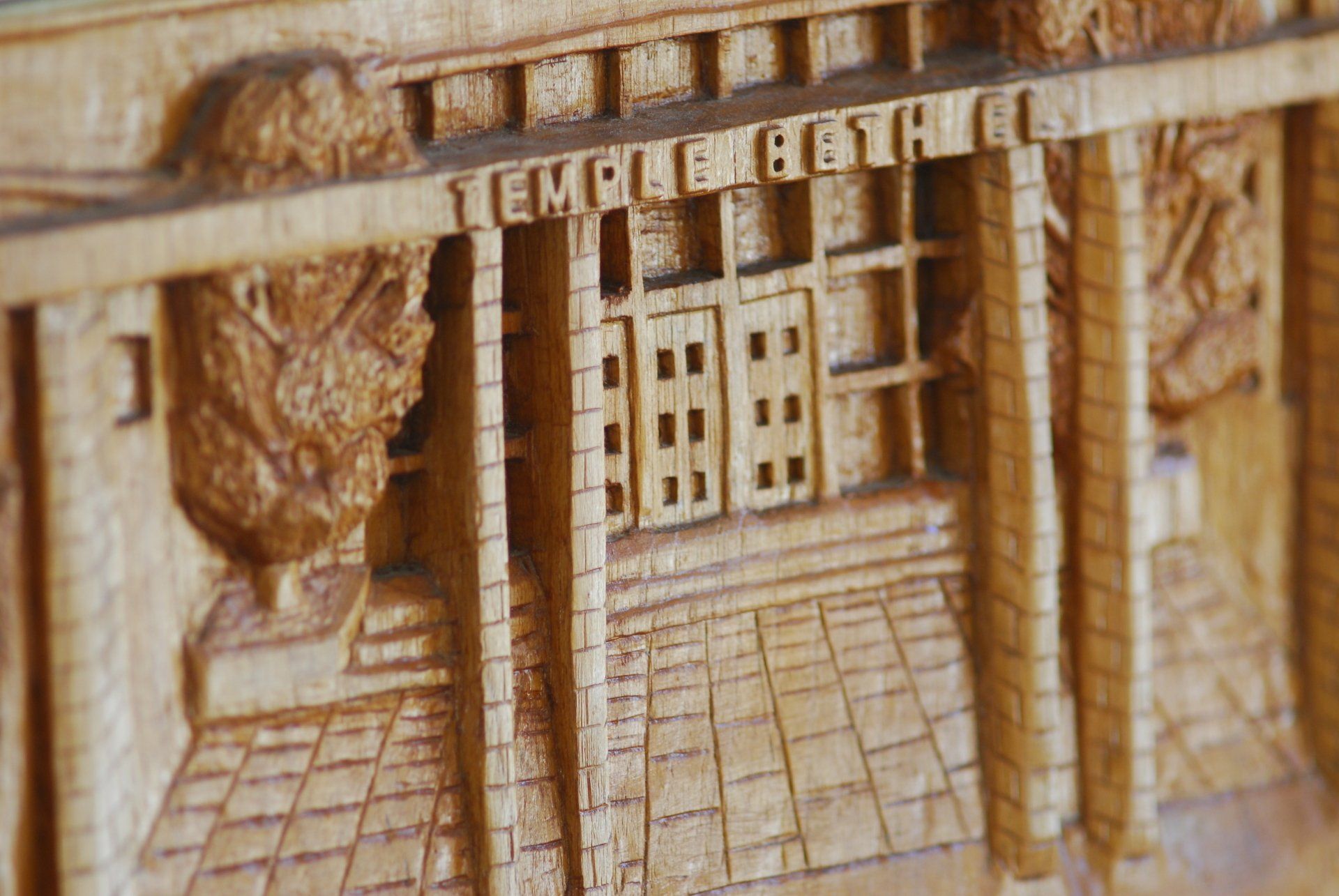 a close up of a wood carving depicting the entrance into Temple Beth El through the courtyard. It says 