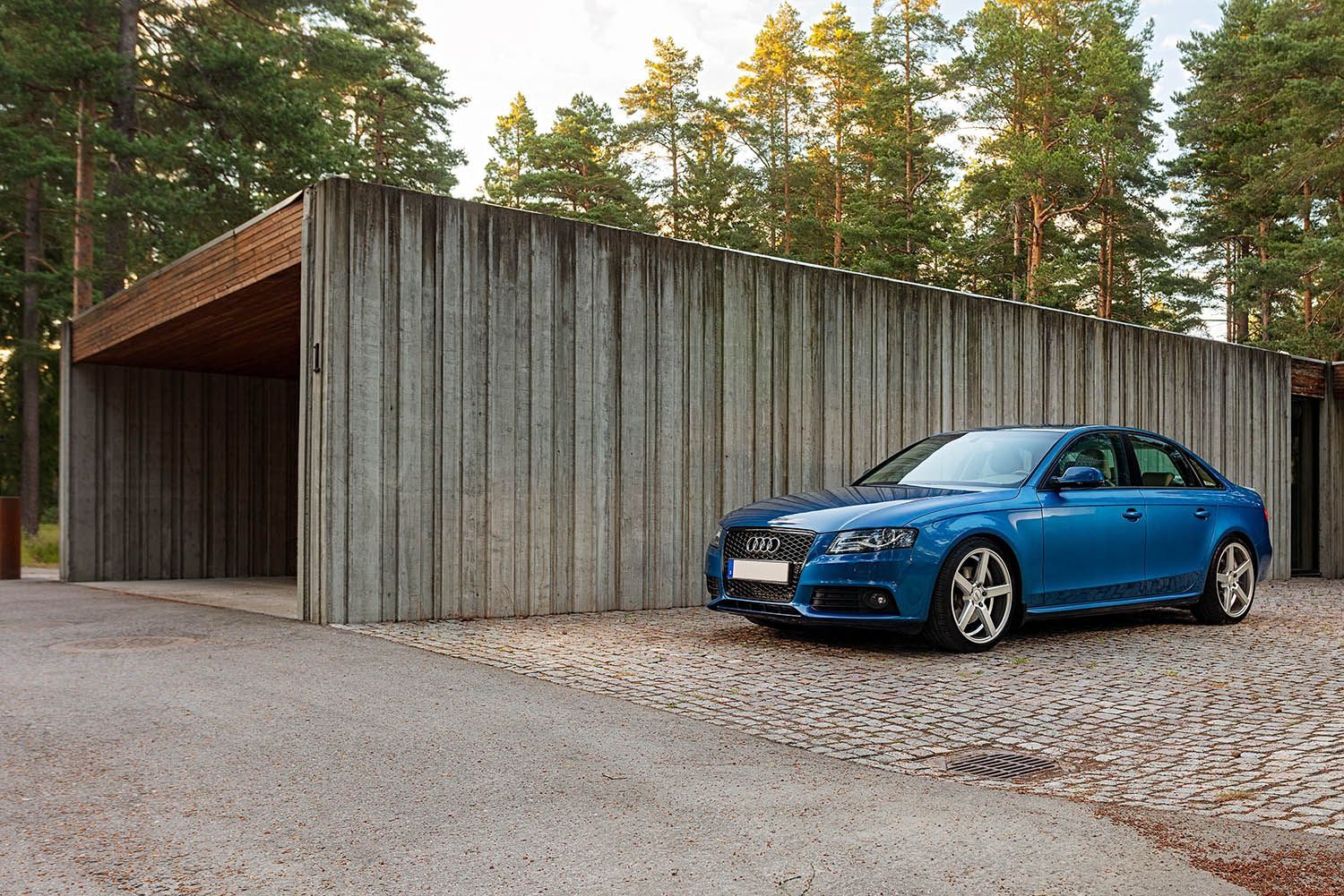 a blue car is parked in front of a carport.
