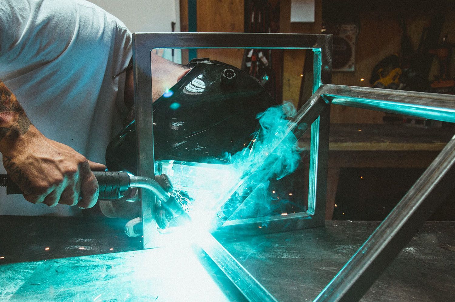 a man is welding a piece of metal in a workshop .