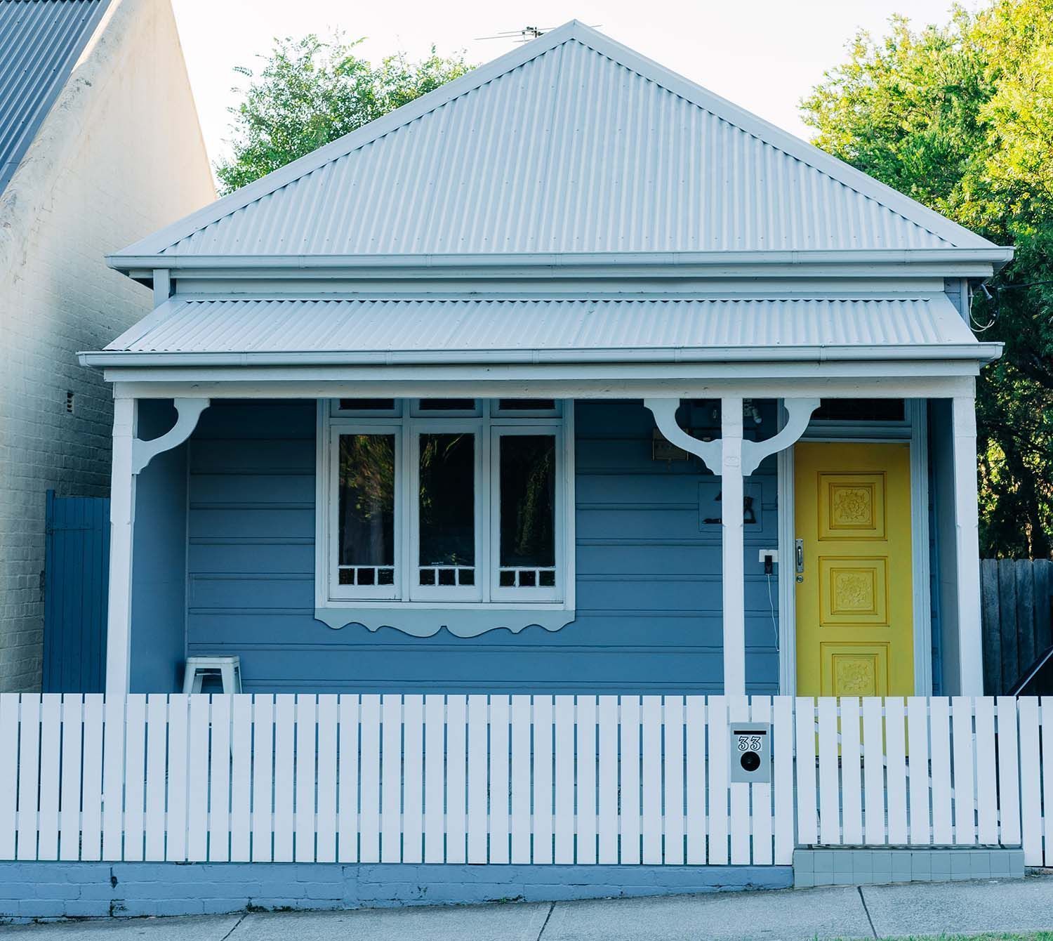 a blue house with a yellow door and a white picket fence
