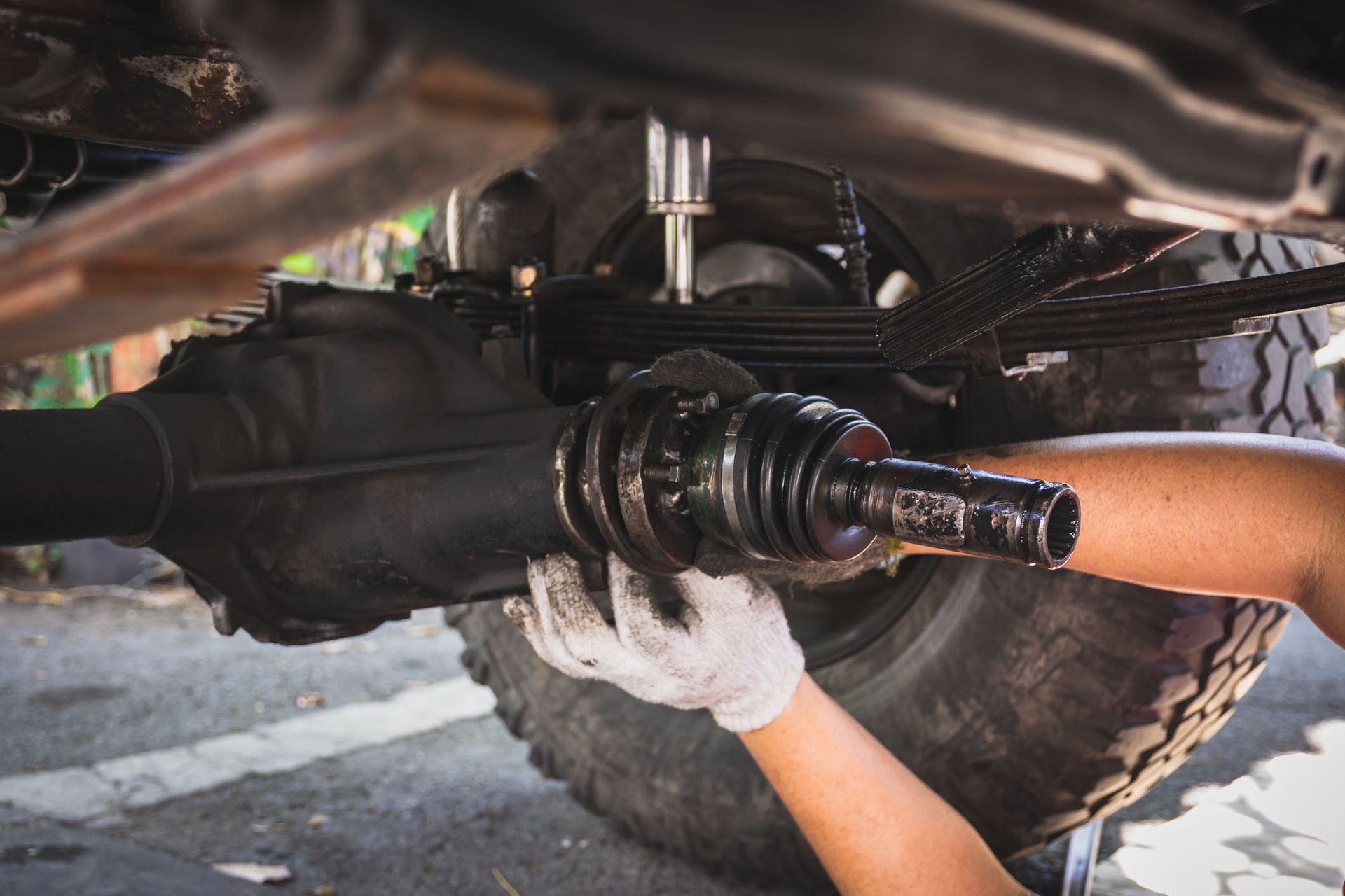 A person is working on the drive shaft of a truck.