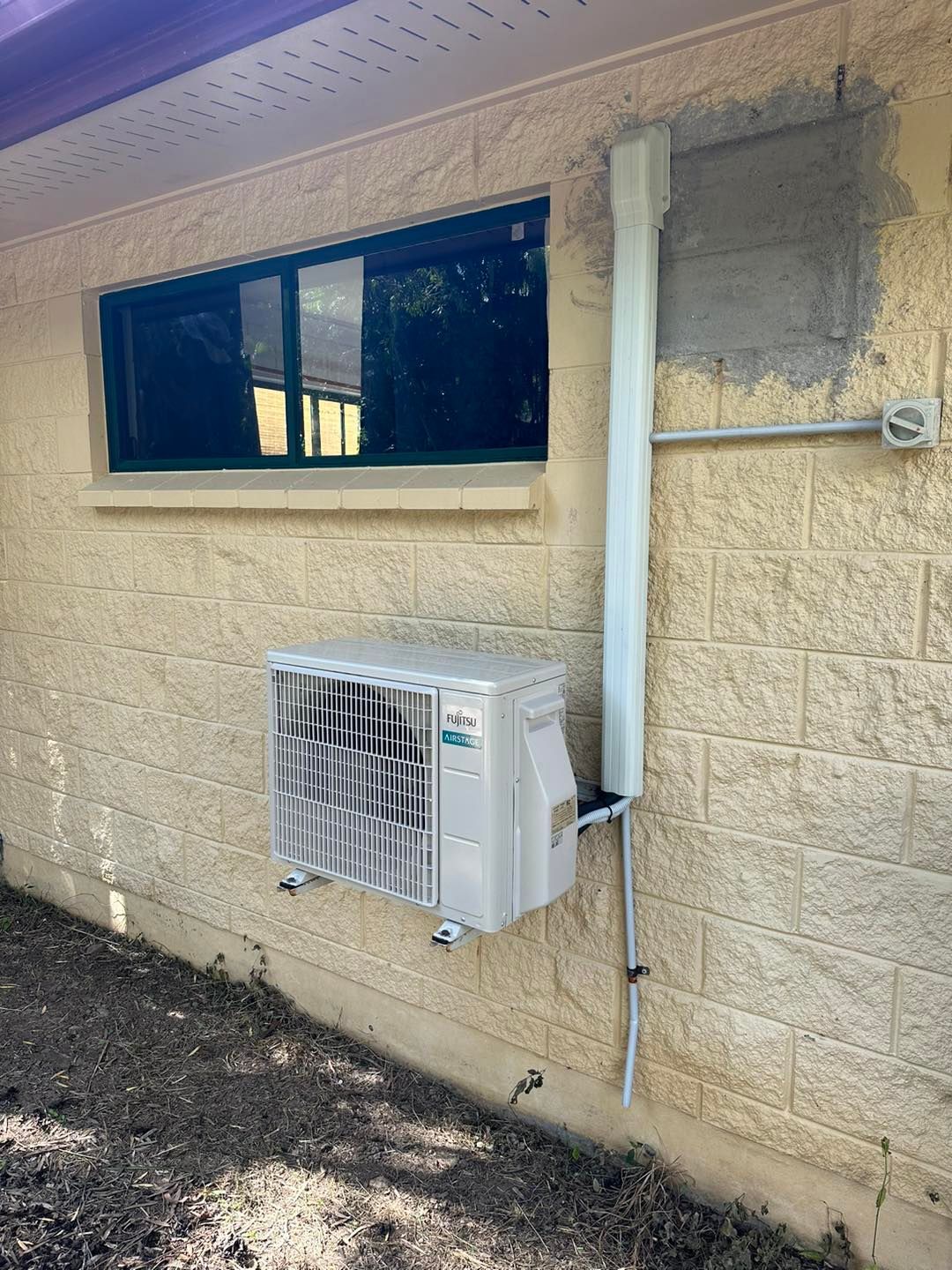 Air Conditioning Unit Mounted on a Textured, Yellow Wall — DJL Refrigeration & Air Conditioning In Airlie Beach, QLD