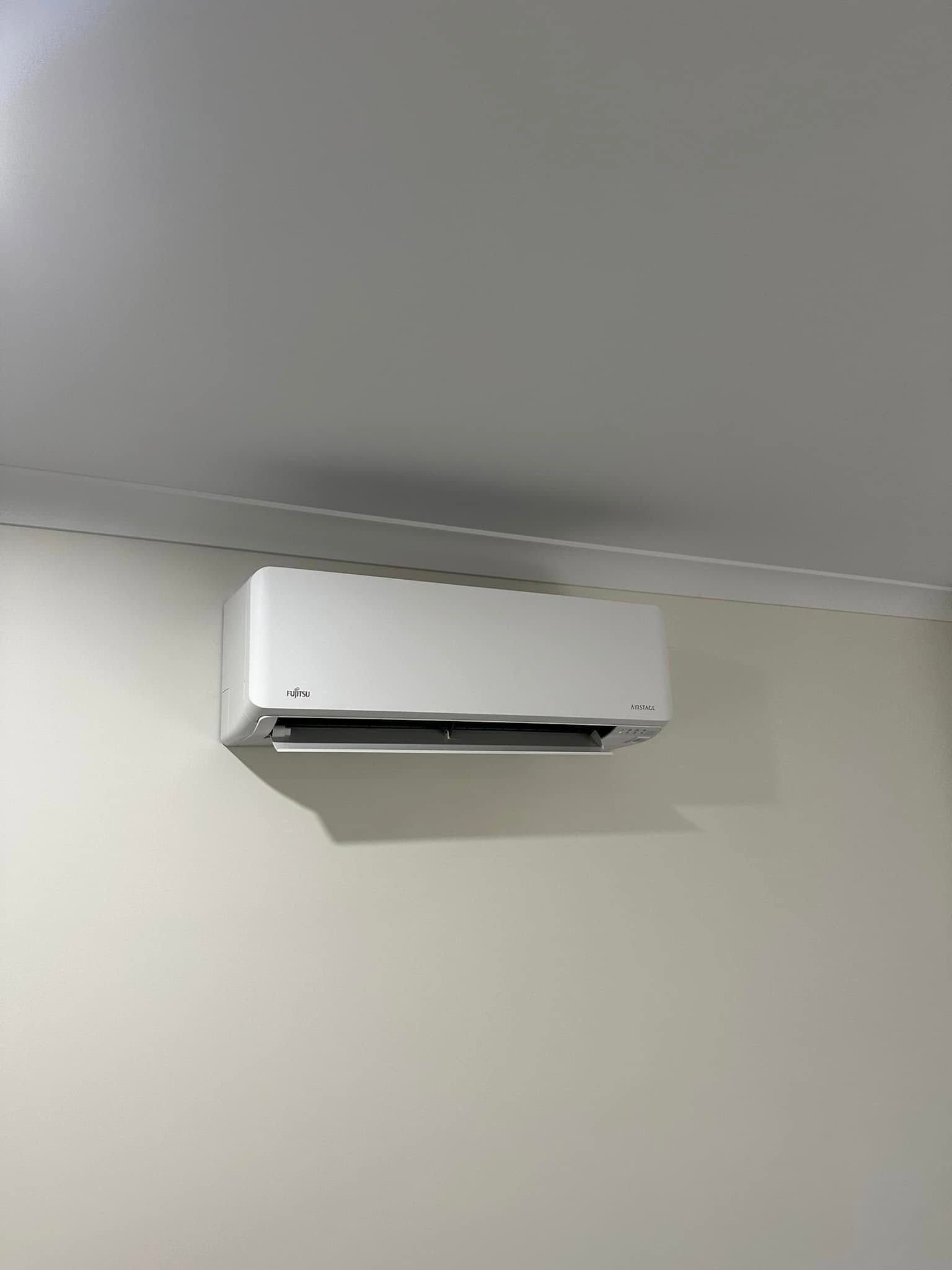 White Air Conditioning Unit Mounted on a Beige Wall — DJL Refrigeration & Air Conditioning In Cannonvale, QLD