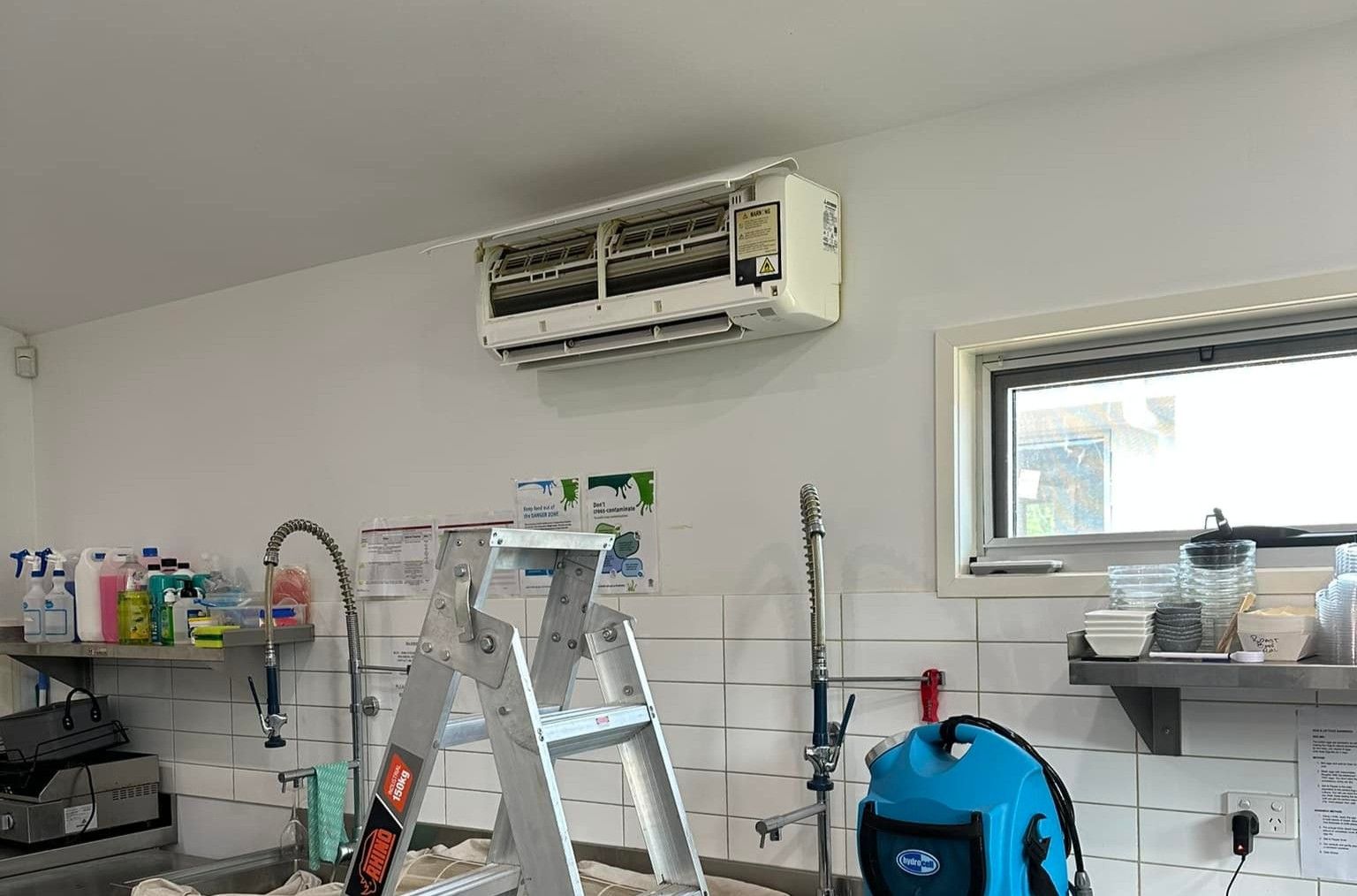 Air Conditioner Being Installed on a White Wall — DJL Refrigeration & Air Conditioning In Cannonvale, QLD