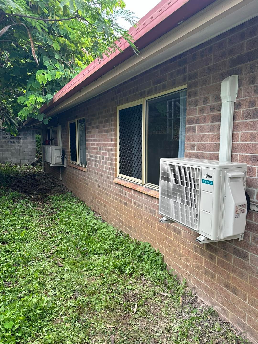 Brick Building With Two Window-mounted Air Conditioners — DJL Refrigeration & Air Conditioning In Proserpine, QLD