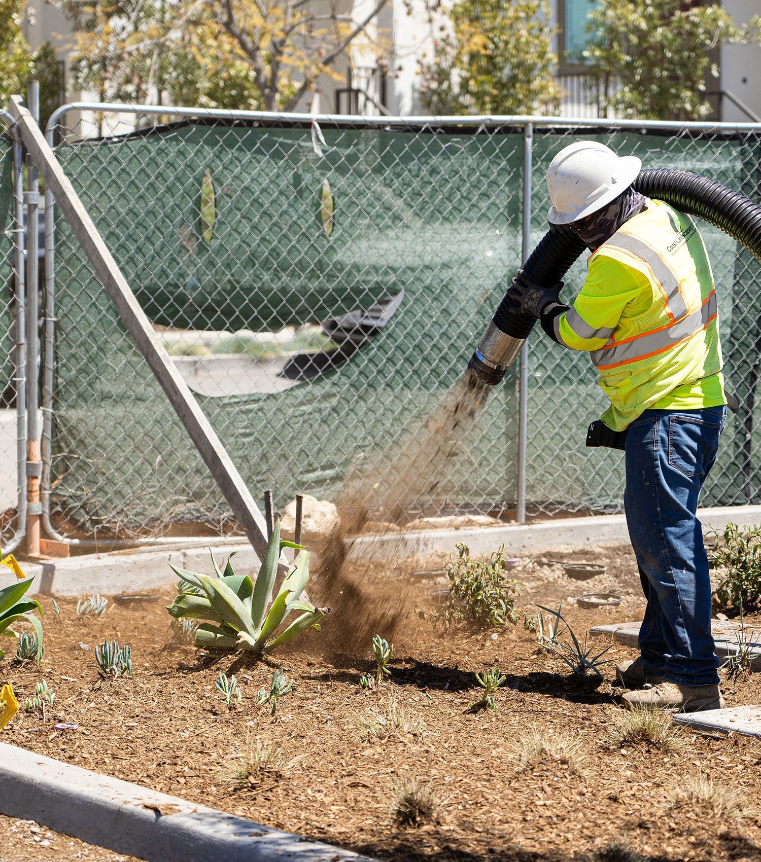 A man is using a vacuum hose to remove dirt from a garden.