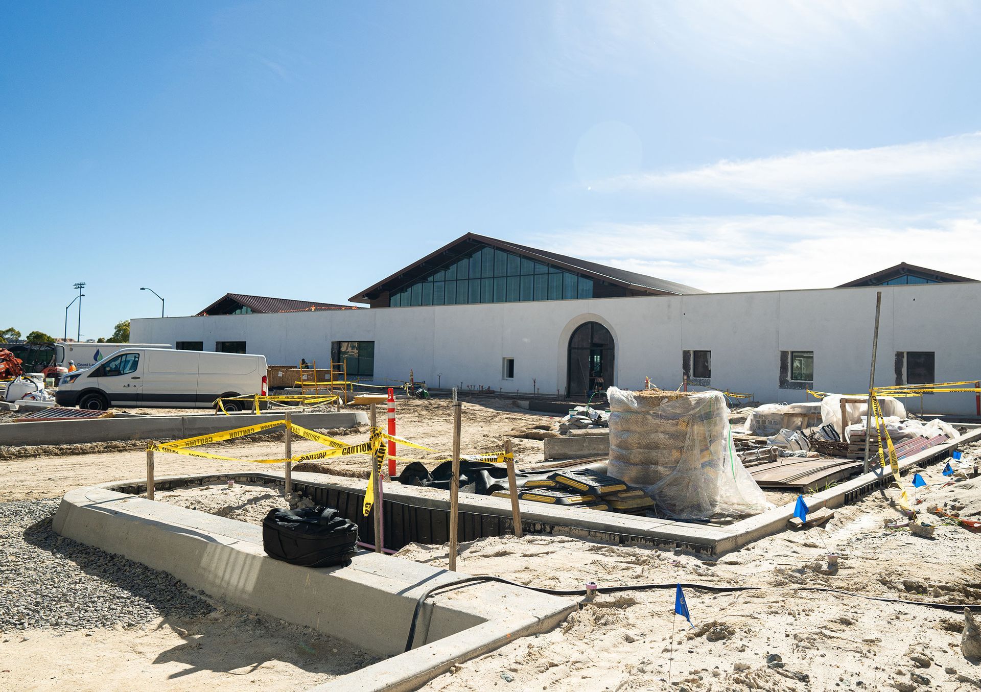 A construction site with a large white building in the background.