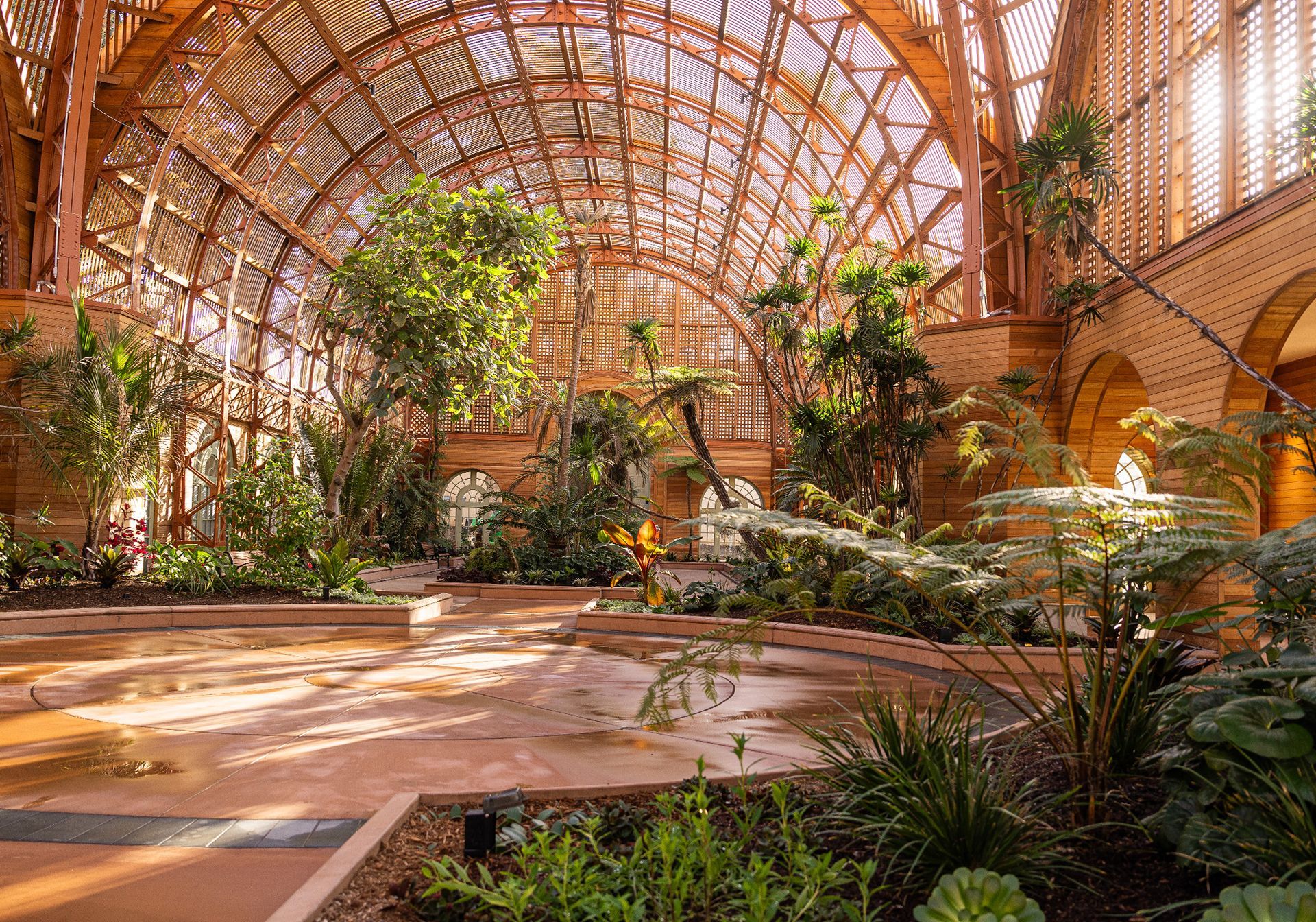 A large building with lots of plants and trees inside of it. San Diego Balboa Park botanical building.