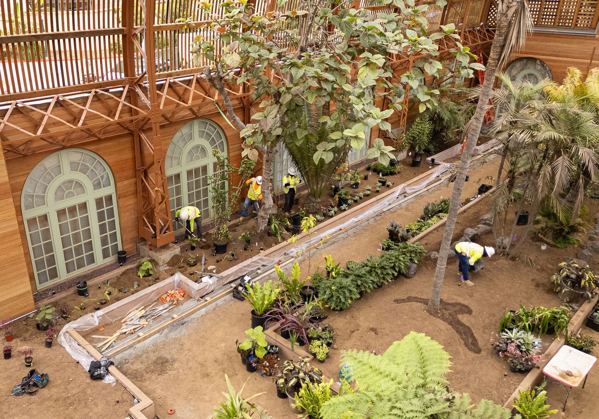 A group of people are working in a garden in front the San Diego Balboa Park botanical building.