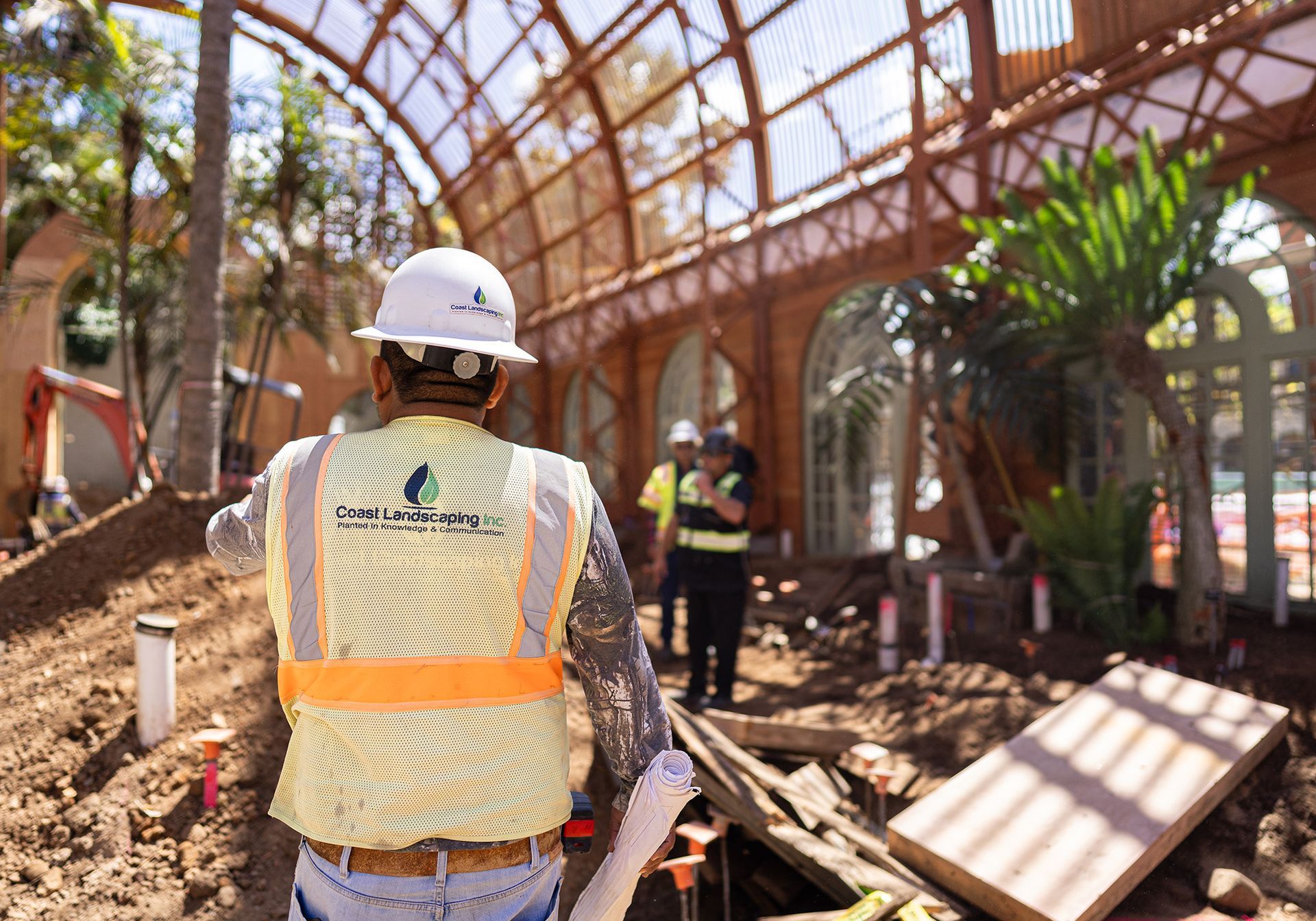 A construction worker is standing in front of the San Diego Balboa Park botanical building under construction.