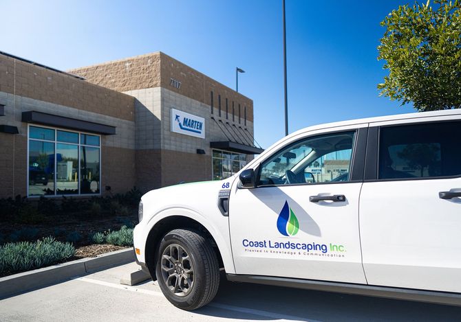 A white landscapers truck is parked in front of a building