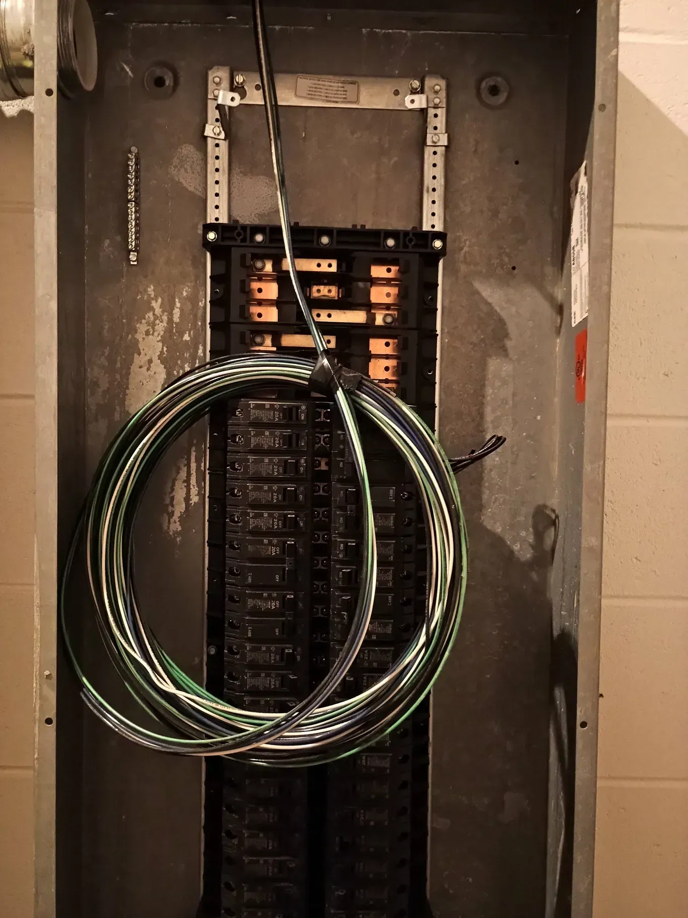 Electrical panel with bundled wires, mounted on a concrete wall.