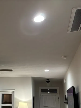 Bright overhead lights in a white ceiling. A doorway and television are visible.